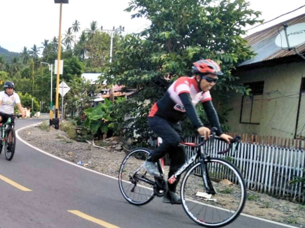 Bupati Bolsel Iskandar Kamaru saat mengelilingi kampung dengan sepeda.
